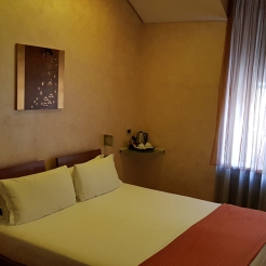 Hotel in Milan. Clean bed, warm coloured wall.